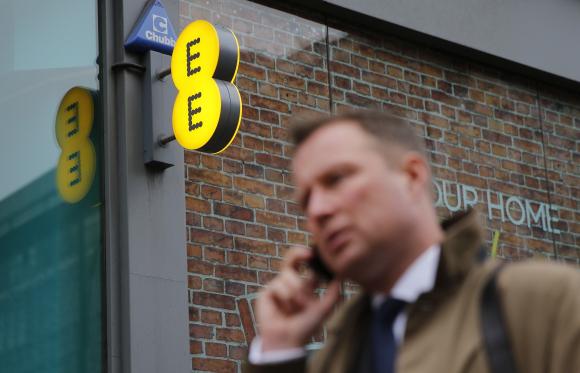 A pedestrian talks on the phone as he walks past an EE shop on Oxford Street in London